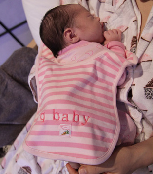 A newborn baby wearing a "q baby" bib.
