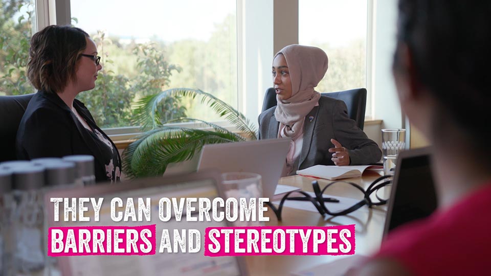 A young girl sits across from a female CEO in a meeting. Text "they can overcome barriers and stereotypes".