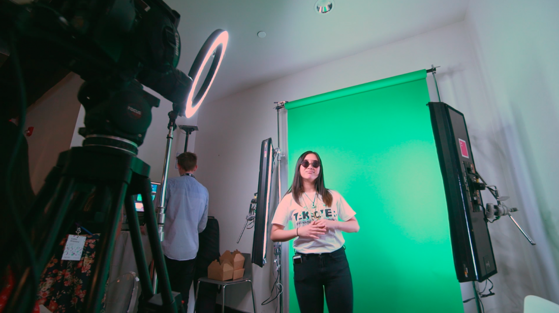Girl stands in front of a green screen activation while cameras roll.